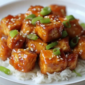 - Firm Tofu - Cornstarch - Vegetable Oil - Honey - Minced Garlic - Soy Sauce - Rice Vinegar - Sesame Oil - Freshly Grated Ginger - Green Onions - Sesame Seeds To make Crispy Honey Garlic Tofu, start with firm tofu. The texture is key for crunch. You will need cornstarch to coat the tofu. This helps it fry up crispy. Vegetable oil is essential for frying. Honey adds sweetness to the dish. Minced garlic packs a flavorful punch. Soy sauce gives a savory depth. Rice vinegar adds a tangy touch. Sesame oil brings a nutty flavor. Freshly grated ginger gives a fresh zest. Green onions add a nice pop of color. Finally, sesame seeds are perfect for garnishing. Each ingredient plays a role in creating a delightful meal. {{ingredient_image_2}} Start by draining the tofu. Remove as much water as you can. Press it tightly for about 15 minutes. This step is key for a crispier bite. After pressing, cut the tofu into bite-sized cubes. Aim for even pieces to help them cook evenly. In a mixing bowl, toss the cubed tofu with cornstarch. Make sure each piece is coated well. This layer helps create that crispy texture we all love. Be gentle while tossing to keep the tofu intact. Heat the vegetable oil in a non-stick skillet over medium-high heat. Wait until the oil shimmers. Carefully place the tofu cubes in a single layer. Avoid overcrowding the pan. Fry each side for about 3-4 minutes until golden brown and crispy. Turn them occasionally for even cooking. Once done, transfer them to a paper towel-lined plate to soak up any extra oil. In a separate bowl, combine honey, minced garlic, soy sauce, rice vinegar, sesame oil, and freshly grated ginger. Whisk until it’s smooth and well-mixed. This sauce brings all the flavors together. In the same skillet, reduce the heat to medium. Pour in the honey garlic sauce and let it simmer for about one minute. You want it to bubble and smell amazing. Carefully add the crispy tofu back into the skillet. Gently toss to coat each piece in the sauce. Cook for another 2-3 minutes until the sauce thickens and clings to the tofu. Remove the skillet from heat and transfer the glazed tofu to a serving dish. For a lovely touch, garnish with sliced green onions and a sprinkle of sesame seeds. This adds crunch and visual appeal. Serve it beautifully on a colorful plate with fluffy jasmine rice. Enjoy every delightful bite! - Importance of Pressing Tofu Pressing tofu is key. It removes extra moisture, which helps the tofu get crispy. Use a tofu press or wrap it in a clean towel. Place something heavy on top for about 15-30 minutes. This step ensures your tofu is firm and ready to fry. - Tips for Coating Coat the tofu gently with cornstarch. Toss it in a bowl until each piece is covered. Be careful not to break the tofu. A thin layer gives a nice crunch when fried. Avoid clumps to ensure even cooking. - Suggestions for Additional Seasonings Add red pepper flakes for a spicy kick. You can also use smoked paprika for a deeper flavor. Fresh herbs like basil or cilantro can enhance the taste. Experiment with these to find what you love best. - Pairing Ideas with Sides Serve your crispy honey garlic tofu with fluffy jasmine rice. Steamed broccoli or snap peas add color and nutrition. You can also pair it with a fresh cucumber salad for a light touch. Pro Tips Press Tofu Well: Ensure the tofu is pressed thoroughly to remove as much moisture as possible. This helps achieve a crispier texture when frying. Control the Heat: Fry the tofu on medium-high heat. Too low will make it soggy, while too high can burn it. Find the sweet spot for perfect crispiness! Fresh Ingredients Matter: Use fresh garlic and ginger for the best flavor in your sauce. They will enhance the overall taste of the dish significantly. Garnish Generously: Don't skimp on the green onions and sesame seeds! They add not only flavor but also a beautiful presentation to your dish. {{image_4}} Want some heat? You can add red pepper flakes. Just mix them into the sauce. Start with a pinch and taste it. You can increase the amount based on your spice level. The spicy flakes will give the dish a nice kick. They blend well with the sweet honey. This variation makes your tofu even more exciting! If you want to keep it vegan, try substituting agave nectar. It has a similar sweetness to honey. Use the same amount as you would honey. Agave nectar will create a smooth sauce. It keeps the dish sweet and tasty. This way, you can enjoy honey garlic tofu without using animal products! Not a fan of tofu? No problem! You can use tempeh or seitan instead. Tempeh has a nutty flavor and a firm texture. Cut it into similar cubes. Seitan is chewy and absorbs flavors well. Both options work great in this dish. They will give you a different texture while keeping the taste delicious! To store your crispy honey garlic tofu, place it in an airtight container. Make sure it cools completely before sealing. This helps to keep it fresh. Store it in the fridge for up to three days. The tofu may soften when stored, but the flavor will still be great. To reheat your tofu while keeping it crispy, use an oven or an air fryer. Preheat the oven to 375°F (190°C). Spread the tofu on a baking sheet in a single layer. Bake for about 10 minutes or until it’s hot and crispy again. If using an air fryer, set it to 350°F (175°C) and cook for about 5-7 minutes. Avoid using a microwave, as it will make the tofu soggy. You can freeze crispy honey garlic tofu, but it may lose some texture. To freeze, place the cooled tofu in a single layer on a baking sheet. Freeze for about an hour or until firm. Then, transfer to a freezer-safe bag. It can stay frozen for up to three months. To thaw, move the tofu to the fridge overnight. Reheat it using the methods mentioned above for the best results. To make tofu crispy, start with firm tofu. You need to drain and press it well. This removes excess moisture. Cut the tofu into even cubes. Toss the cubes in cornstarch. This coating helps create a crunchy texture. Fry the coated tofu in hot oil. Cook until golden brown on all sides. Yes, you can use different sauces! You might try teriyaki or sweet chili sauce. Each option brings a new flavor. Experimenting can lead to tasty surprises. Adjust the sweetness or spice to your liking. Just make sure to coat the tofu well. You can serve honey garlic tofu with fluffy rice. Jasmine rice pairs well with the sauce. You might also add steamed veggies or a fresh salad. Noodles are another great option. For a burst of flavor, try garnishing with herbs. Yes, this recipe is excellent for meal prep! Cook the tofu and sauce ahead of time. Store them separately to keep the tofu crispy. You can warm it up later. This dish stays tasty and fresh for a few days in the fridge. This blog post walks you through creating crispy honey garlic tofu. We covered the essential ingredients, from firm tofu to sesame seeds. You learned how to prepare, coat, and fry the tofu perfectly. We also discussed tasty sauce options and garnishing tips to enhance your dish. Remember, you can customize flavors and use leftovers efficiently. This recipe is perfect for meal prep and pairs well with many sides. Enjoy making this delicious dish and impressing your friends and family!