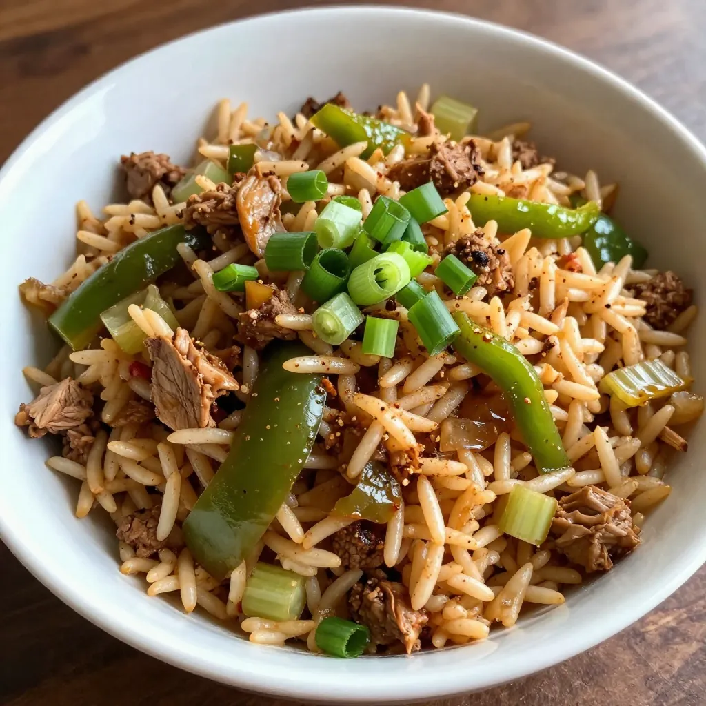 - 1 cup long-grain white rice - 2 cups chicken broth - 1 pound ground turkey or chicken - 1 small onion, finely chopped - 2 cloves garlic, minced - 1 green bell pepper, diced - 1 stalk celery, diced - 1 tablespoon Cajun seasoning - 1 teaspoon dried thyme - 1/2 teaspoon black pepper - 1/2 teaspoon cayenne pepper (adjust based on your spice preference) - 1/2 cup frozen peas - 1/4 cup green onions, sliced (for garnish) - 2 tablespoons olive oil - Salt to taste - For protein, you can try ground beef or pork. - Swap in mushrooms or zucchini for a veggie boost. - Adjust seasonings to fit your taste. Add more cayenne for spice. - Use vegetable broth for a lighter flavor. Cajun dirty rice is all about flavor. You want bold, rich tastes. Each ingredient plays a big role. The chicken broth adds depth. The ground turkey or chicken gives it heartiness. Fresh veggies bring color and crunch. The spices? They wake up your taste buds. When picking your ingredients, focus on quality. Fresh veggies and good broth make a big difference. You can play around with flavors too. Want it spicy? Add more cayenne. Prefer it mild? Cut back on the heat. This dish is flexible. You can use what you have. If you don’t like peas, leave them out. Don’t have green onions? No problem. Just make it your own! {{ingredient_image_2}} - Begin by rinsing the rice under cold water. Make sure the water runs clear. This step removes excess starch, which helps the rice stay fluffy. - After rinsing, drain the rice in a colander. Set it aside while you prepare the broth. - In a medium saucepan, bring 2 cups of chicken broth to a boil. This broth adds great flavor to the rice. - Once the broth is boiling, add the rinsed rice. Stir it well and cover the pan with a lid. - Lower the heat and let it simmer for about 15-20 minutes. The rice should be tender and absorb all the broth. - While the rice cooks, heat 2 tablespoons of olive oil in a large skillet over medium heat. - Add 1 small finely chopped onion, 2 minced garlic cloves, 1 diced green bell pepper, and 1 diced stalk of celery to the skillet. - Sauté the veggies for about 5 minutes. You want them soft and fragrant, which adds depth to your dish. - Now, add 1 pound of ground turkey or chicken to the skillet. Cook it until it turns brown, breaking it apart as it cooks. This should take about 6-8 minutes. - Once the meat is cooked, sprinkle in 1 tablespoon of Cajun seasoning, 1 teaspoon of dried thyme, 1/2 teaspoon of black pepper, and 1/2 teaspoon of cayenne pepper, adjusting for heat. - Stir everything well, allowing the meat to soak in the spices for about 2 minutes. - Lower the heat and add the cooked rice and 1/2 cup of frozen peas to the skillet. Gently fold them into the mixture until they are well combined. - Cook for another 3-5 minutes until the peas are warmed through. - Finally, taste the dish. Adjust the salt as needed to reach your desired flavor. - Remove the skillet from the heat and let it rest for a few minutes. This resting time helps the flavors blend together nicely. To make your Cajun dirty rice shine, balance your seasonings. Use a mix of Cajun seasoning, thyme, black pepper, and cayenne. Start with a tablespoon of Cajun seasoning, then taste. If you want more heat, add more cayenne pepper. This way, you control the spice level and keep the dish tasty. For meal prep, chop your vegetables in advance. Store them in the fridge. You can also cook the rice a day ahead. This cuts down your cooking time. Just reheat the rice when you are ready to mix it with the meat and veggies. Serve your Cajun dirty rice in shallow bowls. This makes each plate look inviting. Top it with sliced green onions for a bright finish. You can also sprinkle extra Cajun seasoning to enhance the look. If you love heat, offer hot sauce on the side. This lets everyone spice it up to their liking. For a complete meal, serve with a fresh salad or crusty bread. These sides balance the flavors and make it even more delicious. Pro Tips Rinse Your Rice: Thoroughly rinsing the rice removes excess starch, helping to prevent it from becoming sticky and ensuring a perfect texture. Adjust the Heat: The amount of cayenne pepper can be tailored to your spice preference, so taste as you go to find your ideal balance. Incorporate Fresh Herbs: For added freshness, consider mixing in chopped fresh parsley or cilantro just before serving for a burst of flavor. Let It Rest: Allowing the dish to rest after cooking helps the flavors meld together, enhancing the overall taste of the dirty rice. {{image_4}} You can make this dish plant-based by using lentils instead of meat. Cooked lentils add texture and protein. You can also use plant-based ground meat. Mix in a medley of vegetables like carrots, zucchini, or mushrooms. This adds flavor and color to your dirty rice. Want more heat? Just add more cayenne or hot sauce. Adjust the spice to your taste. For a fresh kick, toss in diced jalapeños or any chili pepper you like. This will make your Cajun dirty rice even more exciting! If you want to save time, try a one-pot method. You can cook everything in a large pot. Just add all the ingredients and let them simmer. Or, use a rice cooker for easier preparation. It makes cleanup simple and keeps all the flavors locked in! To store leftovers in the fridge, place the Cajun dirty rice in an airtight container. Make sure it cools down first. You can keep it fresh for about 3 to 4 days. When you are ready to eat again, check the smell and look for any signs of spoilage. If it looks good, reheat it well before serving. To freeze Cajun dirty rice, use freezer-safe bags or containers. Portion it out for easy meals later. Squeeze out any extra air to prevent freezer burn. You can freeze it for up to 2 months. When it's time to eat, thaw it overnight in the fridge. To reheat, warm it gently in a pan or microwave. Add a splash of broth to keep it moist. Enjoy your tasty meal! Cajun Dirty Rice is a tasty dish from Louisiana. It combines rice with ground meat and spices. The rice gets its "dirty" name from the meat and spice mixture that colors it. This dish shows the rich culture of Cajun cooking, which blends French, African, and Spanish flavors. It's hearty and full of flavor, often served at family gatherings and festivals. Yes, you can make Cajun Dirty Rice ahead of time. Prepare the dish and let it cool. Store it in an airtight container in the fridge for up to three days. When you're ready to eat, reheat it in a pan over low heat. Add a splash of chicken broth to keep it moist. Stir often until it's hot and tasty. Cajun Dirty Rice pairs well with many sides. Here are some ideas: - Cornbread: Soft, sweet cornbread adds a nice touch. - Collard Greens: This dish brings a fresh, earthy flavor. - Fried Green Tomatoes: Crispy tomatoes add crunch. - Coleslaw: A cool, creamy slaw balances the spice. These sides complement the bold flavors of Cajun Dirty Rice and make a complete meal. Cajun dirty rice combines simple ingredients for a flavorful dish. We went over the main components like rice, turkey, and spices. You learned about tips for better seasoning and ways to adapt the recipe. Keep in mind that variations exist for different tastes. Whether you prefer a vegetarian option or an extra kick of spice, you can adjust it easily. Store leftovers well for later enjoyment. I hope you feel inspired to create your own version! Enjoy your cooking!